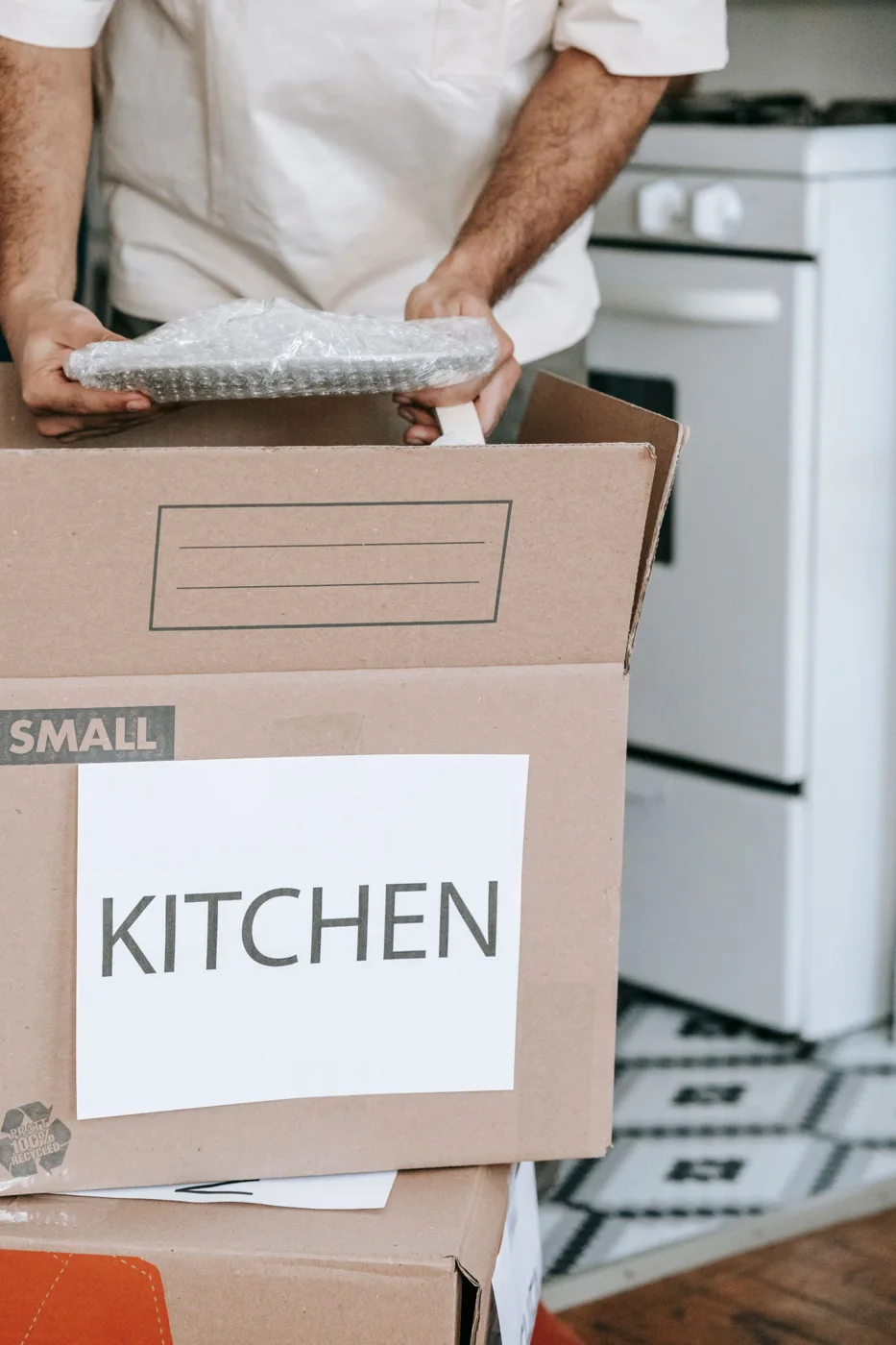 Kitchenware being packed beside a labelled kitchen box