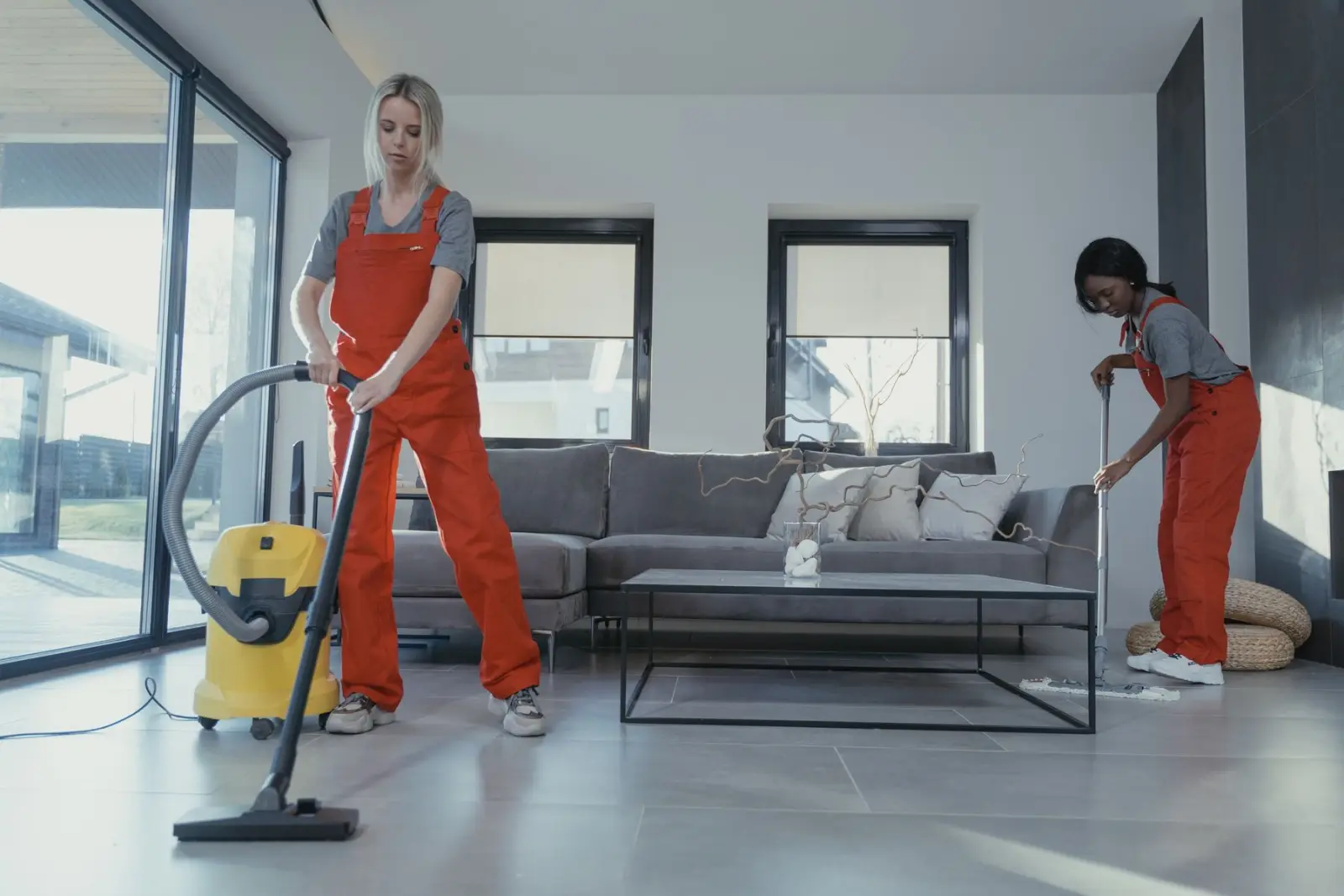 Two cleaners vacuuming and mopping a living room