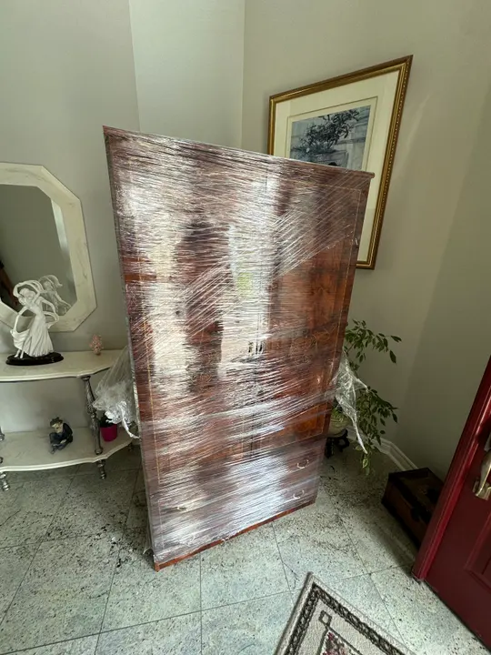 A wooden cabinet wrapped for transport inside a home