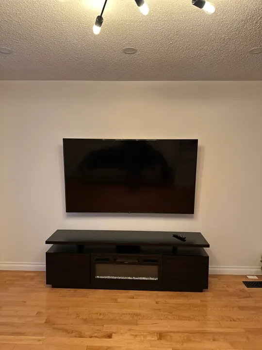 A wall-mounted television above a dark media console in a living room