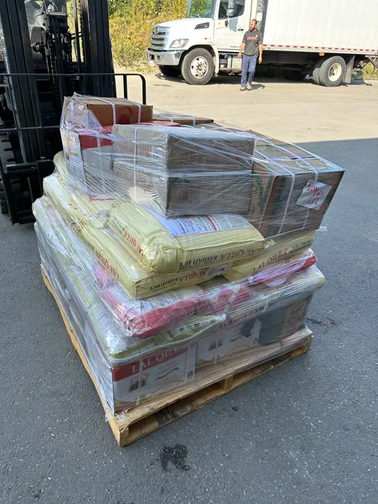 Wrapped boxes and furniture secured on a pallet beside a moving truck