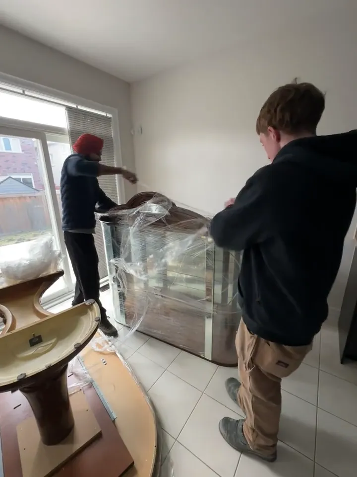 Optimum crew members wrapping furniture before a move
